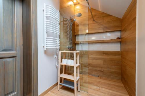 een badkamer met een glazen douche en een houten muur bij Willa Lavinka in Zawoja