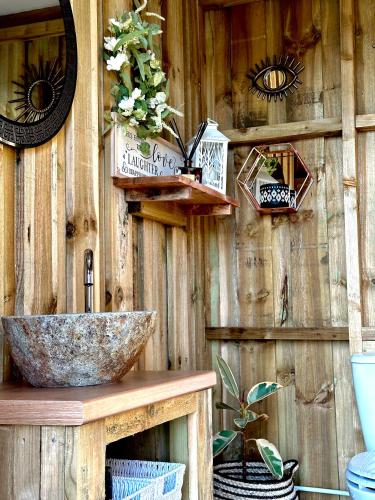 a bathroom with a sink and a wooden wall at Deerstone Glamping-Pinhaw Beacon dome Hot tub in Earby