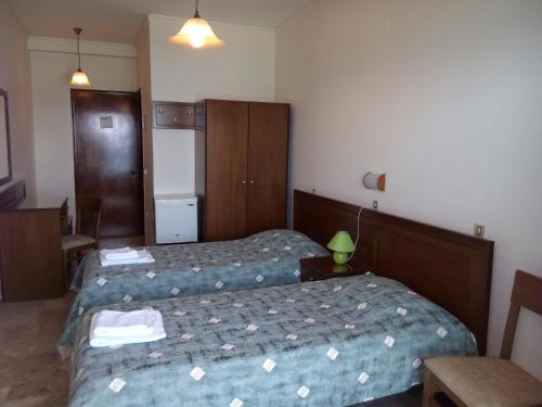 a hotel room with two beds and a refrigerator at Akrogiali in Kyparissia