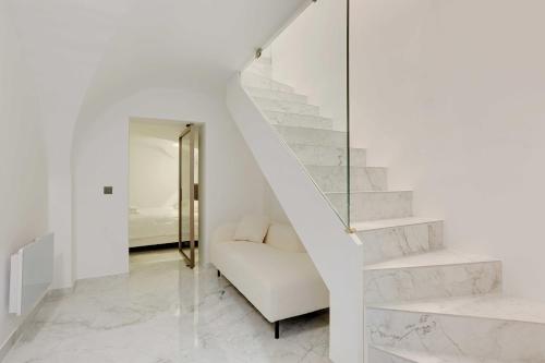 un escalier blanc dans une pièce blanche avec un canapé blanc dans l'établissement Beautiful 1BR6P - Montorgueil RDC, à Paris