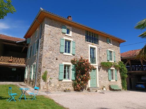 a stone house with green shutters and a table and chairs at Baladous in Montgaillard-de-Salies