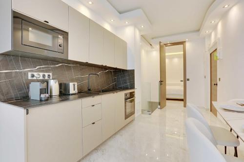 une cuisine avec des armoires blanches et un évier dans l'établissement Beautiful 1BR6P - Montorgueil RDC, à Paris