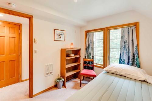 ein Schlafzimmer mit einem Bett, einem Fenster und einem roten Stuhl in der Unterkunft Juneau Vacation Home Stunning View and Beach Access in Mendenhaven