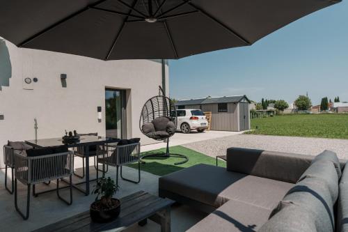 a patio with a couch and a table and an umbrella at La Stanza del Relax in San Donà di Piave