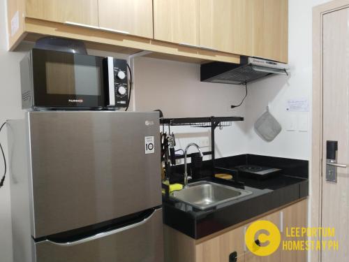 a small kitchen with a microwave and a refrigerator at F524 Place at SMDC Cheer Residences by Lee Portum in Marilao