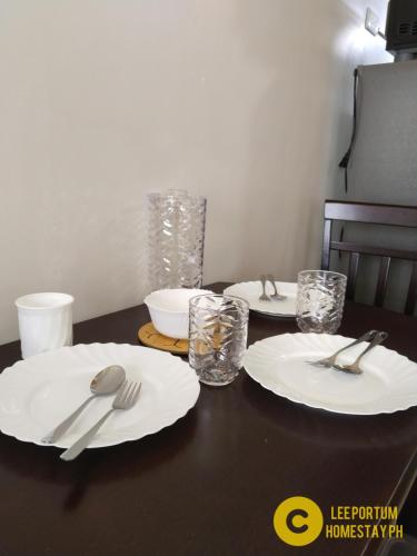 a table with white plates and silverware on it at F524 Place at SMDC Cheer Residences by Lee Portum in Marilao