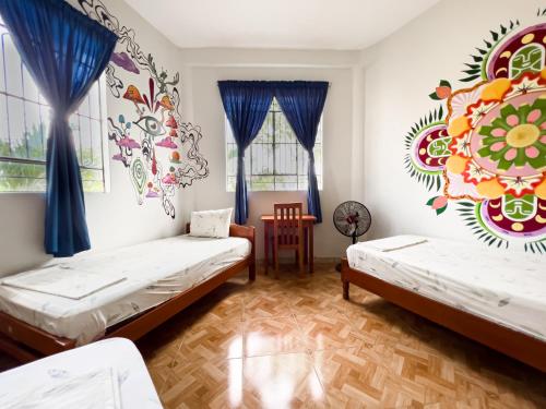 two beds in a room with a mural on the wall at El Mural Backpackers in Tarapoto
