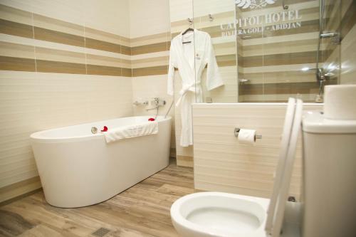 uma casa de banho com uma banheira, um WC e um lavatório. em Capitole Hotel em Abidjan