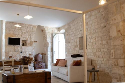 Dimore Storiche Casalnuovo في كونفيرسانو: غرفة معيشة مع أريكة بيضاء وجدار من الطوب