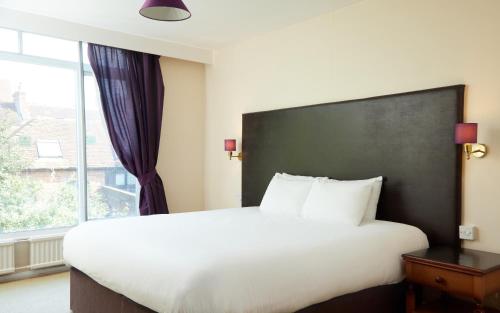 a bedroom with a large white bed and a window at Bear Hotel by Greene King Inns in Havant