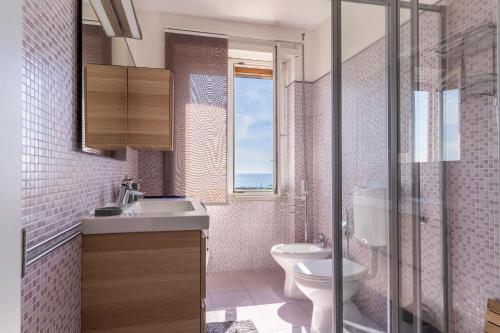een badkamer met een wastafel, een toilet en een raam bij Livorno - Sea View Apartment! in Livorno