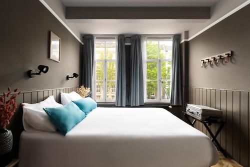 a bedroom with a large white bed with blue pillows at HEGRA by Stanley Collection in Amsterdam
