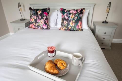 a tray with donuts and a cup of coffee on a bed at Vaughan Lodge- Stunning 2 Bedroom Duplex Apartment in Malvern Wells