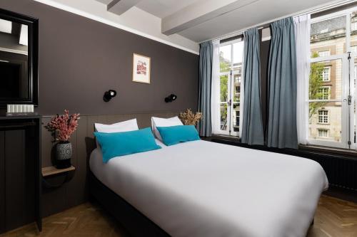 a bedroom with a large white bed with blue pillows at HEGRA by Stanley Collection in Amsterdam