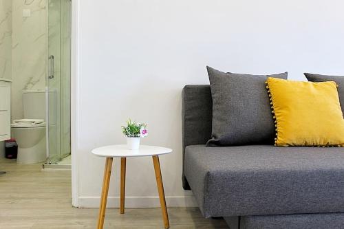 ein graues Sofa mit einem gelben Kissen und einem Tisch in der Unterkunft Plano C 2 Oporto Downtown in Porto