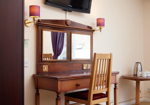 a wooden desk with a mirror and a chair at Bear Hotel by Greene King Inns in Havant