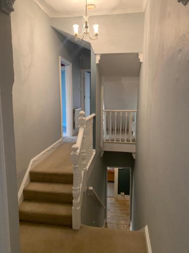 a staircase in a home with a chandelier at Strawberry Fields - CENTRAL TORQUAY in Torquay