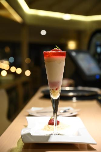 a drink with a strawberry on a plate on a table at Kavos Hotel & Suites in Stavros