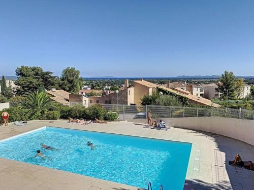 une grande piscine avec des gens dans l'eau dans l'établissement Appartement entre ciel et mer le grand large, à Hyères