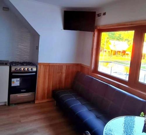 sala de estar con sofá negro y ventana en Cabañas Agua Divina, en Recinto