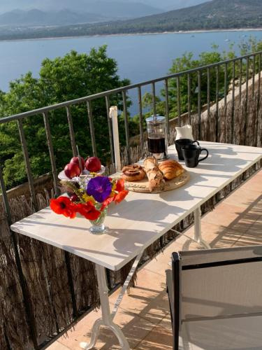 une table avec une assiette de nourriture et de fleurs sur un balcon dans l'établissement Studio Castille, à Calvi