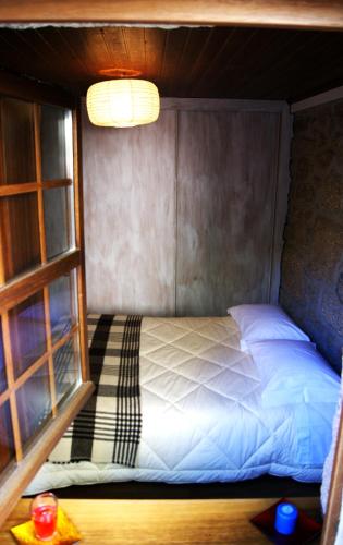 a bed in a small room with a window at Cantinho Santiago in Belmonte