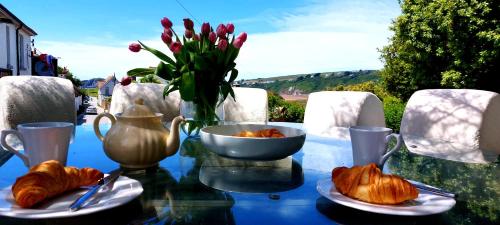 una mesa de cristal con cruasanes y un jarrón de flores en Bantham House, Bantham, South Devon - a few steps from golden sandy beaches en Bigbury-on-Sea
