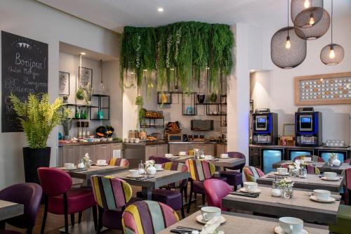 a restaurant with tables and chairs and a kitchen at Best Western Plus Nice Cosy Hotel in Nice