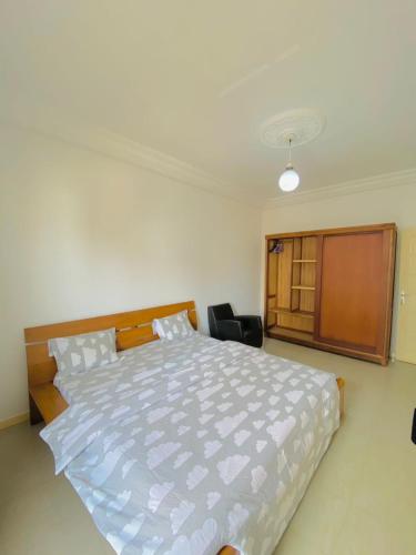 a bedroom with a large white bed and a chair at Appartement xandra in Dakar