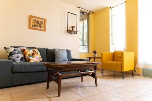 a living room with a blue couch and a yellow chair at המקום של מירה'לה - חדרי אירוח קסומים, רומנטיים ומבודדים בחיק הטבע in Mattat