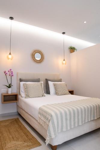 a white bedroom with a large white bed and a mirror at Olivia’s House in Kavos