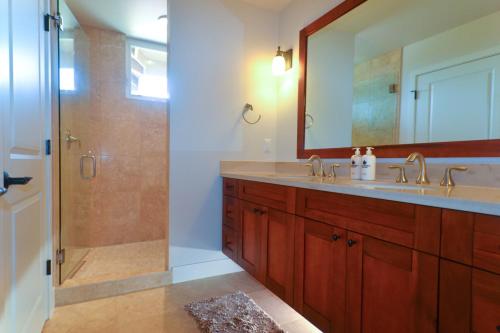 Un baño con lavabo y ducha con espejo. en Pili Mai 8I, en Koloa