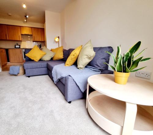 a living room with a blue couch with yellow pillows at Cityscape Haven: 1 Bedroom Apartment with Terrace and City view in Bournemouth