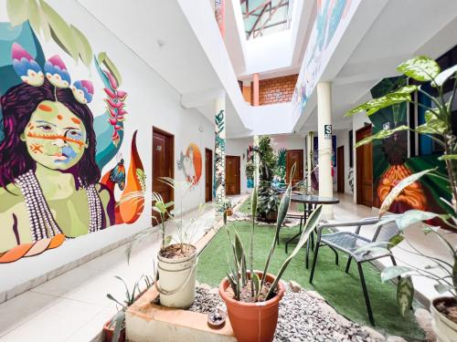 a room with plants and paintings on the walls at El Mural Backpackers in Tarapoto