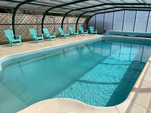- une piscine avec des chaises bleues dans un bâtiment dans l'établissement Domaine des Trois Rivières, à Merlevenez