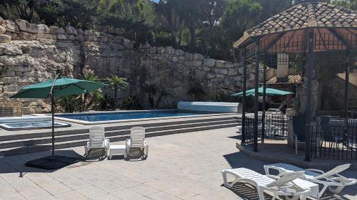 a swimming pool with chairs and a gazebo and a group oficans at El Collado in Cullera