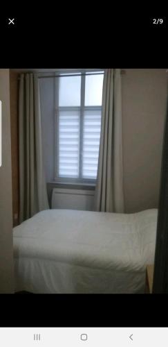 une chambre avec un lit blanc avec une fenêtre dans l'établissement Chez Philippe, à Eaux-Bonnes