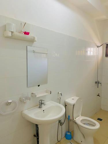Baño blanco con aseo y lavamanos en Appartement xandra 2, en Dakar