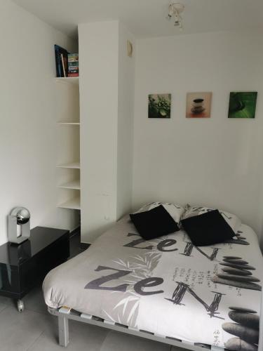 - une chambre blanche avec un lit et des oreillers noirs dans l'établissement Grand studio calme bien situé, à Cagnes-sur-Mer