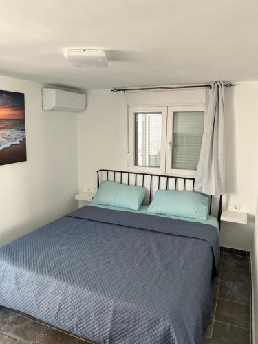 - une chambre avec un lit doté de draps bleus et une fenêtre dans l'établissement Casa Manoli, à Torremolinos