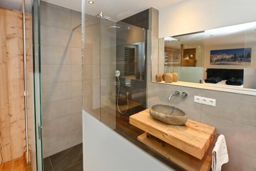 uma casa de banho com uma cabina de duche em vidro e uma tigela numa mesa de madeira em Apartment Bergliebe em Sankt Gallenkirch