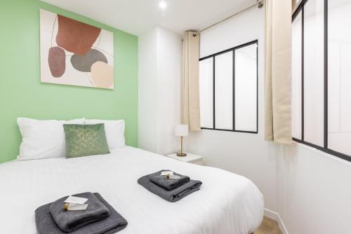 une chambre avec un lit blanc avec deux serviettes dessus dans l'établissement Nets Inn apartments - Buttes Chaumont C, à Paris