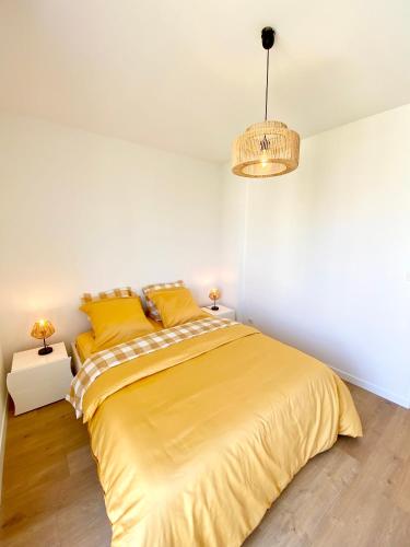 - une chambre dotée d'un lit avec des draps jaunes et un lustre dans l'établissement Magnifique 3P neuf proche mer, à Nice