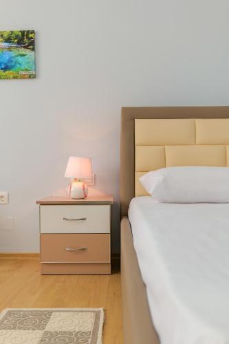 a bedroom with a bed and a nightstand with a lamp at Villa All Season in Sarandë