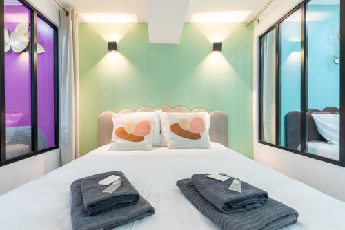 een slaapkamer met een bed met handdoeken en ramen bij Nets Inn - Botzaris in Parijs