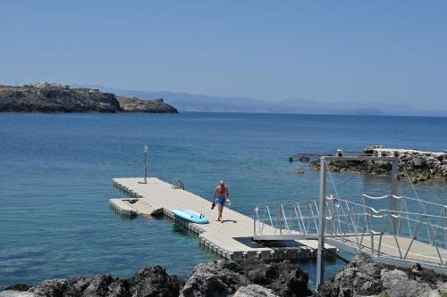 a man walking on a dock in the water at Kavos Hotel & Suites in Stavros