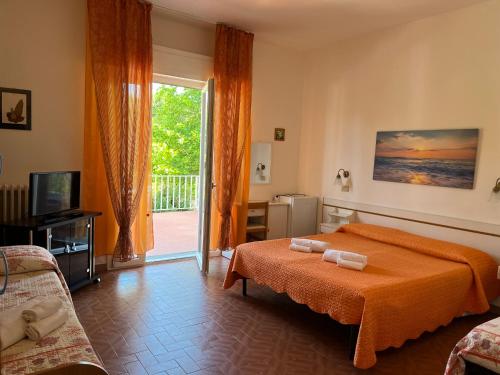 a bedroom with a bed with an orange blanket at Hotel Ellymar in Vada