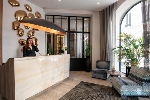 a woman talking on a cell phone in a lobby at Best Western Plus Nice Cosy Hotel in Nice