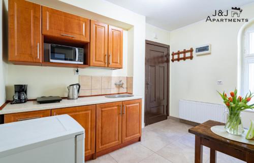 a kitchen with wooden cabinets and a kitchen table at J&J Apartments, Szeroka 25 Apartament 13 in Toruń