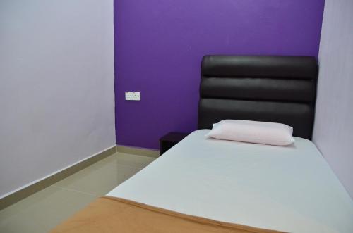 a bedroom with a bed and a black chair at Deena Hotel Bajet in Gua Musang